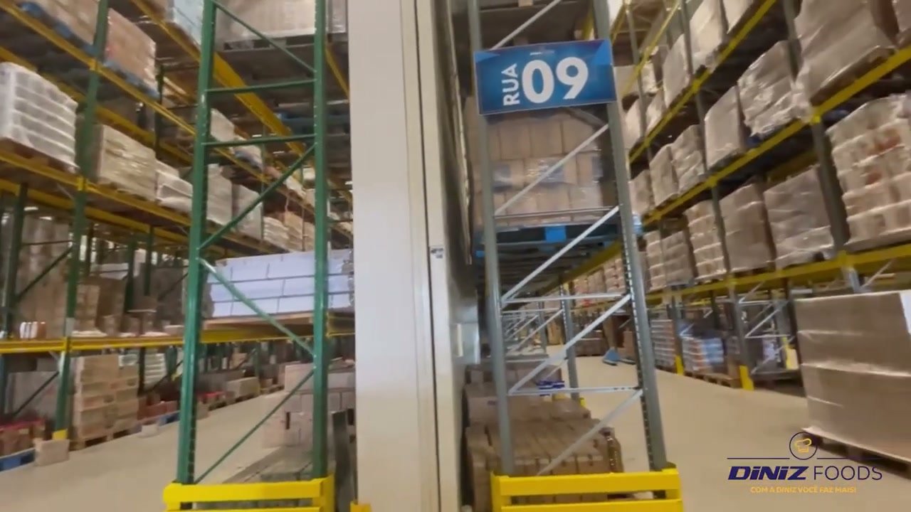 Corredor do centro de distribuição da Diniz Foods, com prateleiras altas e paletes organizados por rua